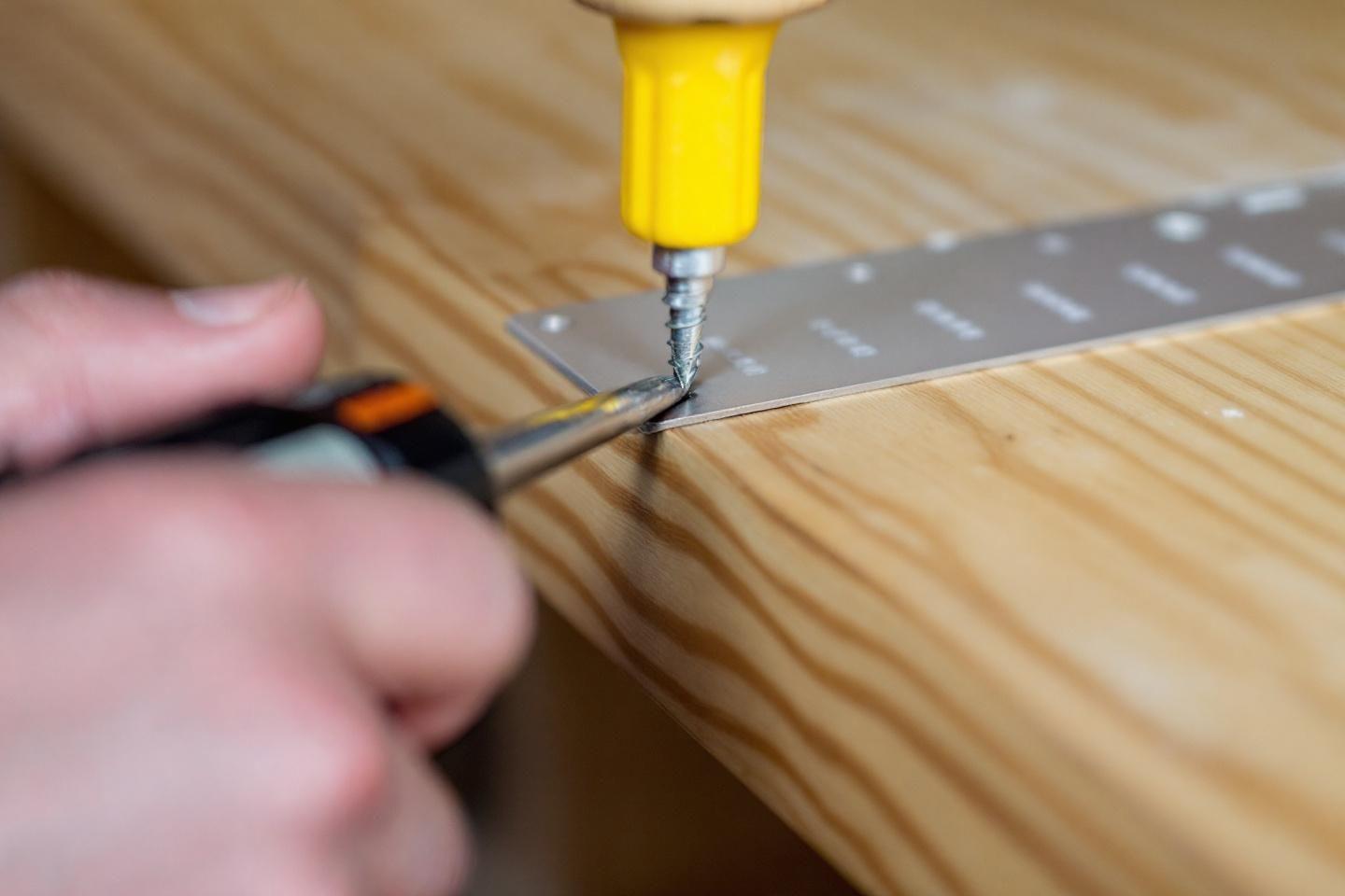 Gros plan d'une visseuse jaune perçant une planche