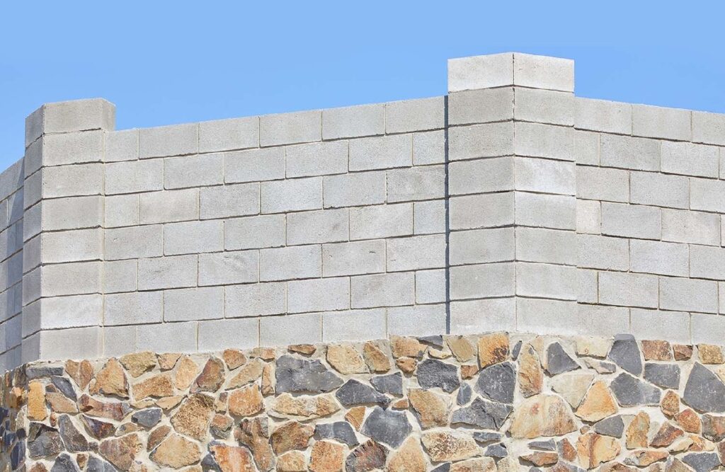 mur en parpaing posé sur un mur en pierre