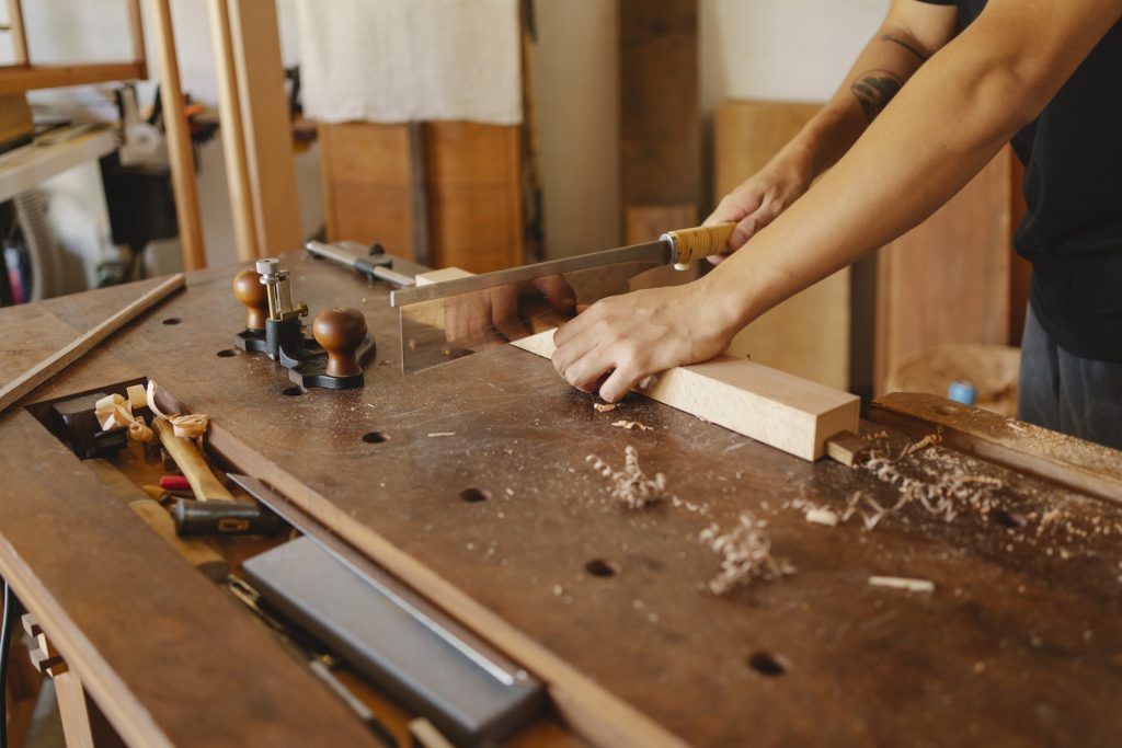 Travailleur du bois coupant une planche de bois à l'aide d'une scie à métaux