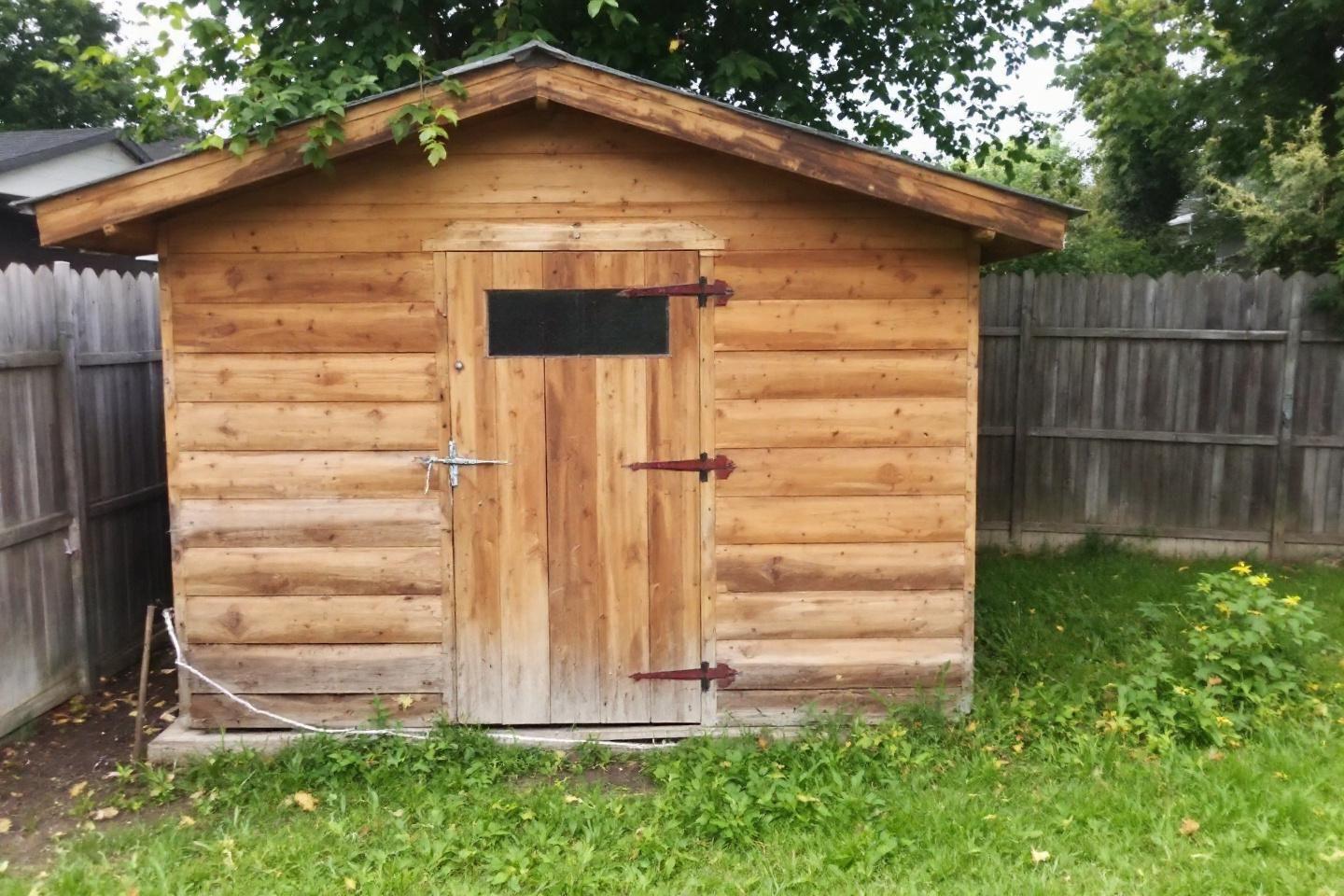 Cabane de jardin en bois avec porte, entour&eacute;e de cl&ocirc;ture