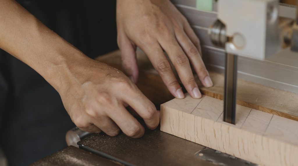 Charpentier coupant un bloc de bois avec une scie à ruban